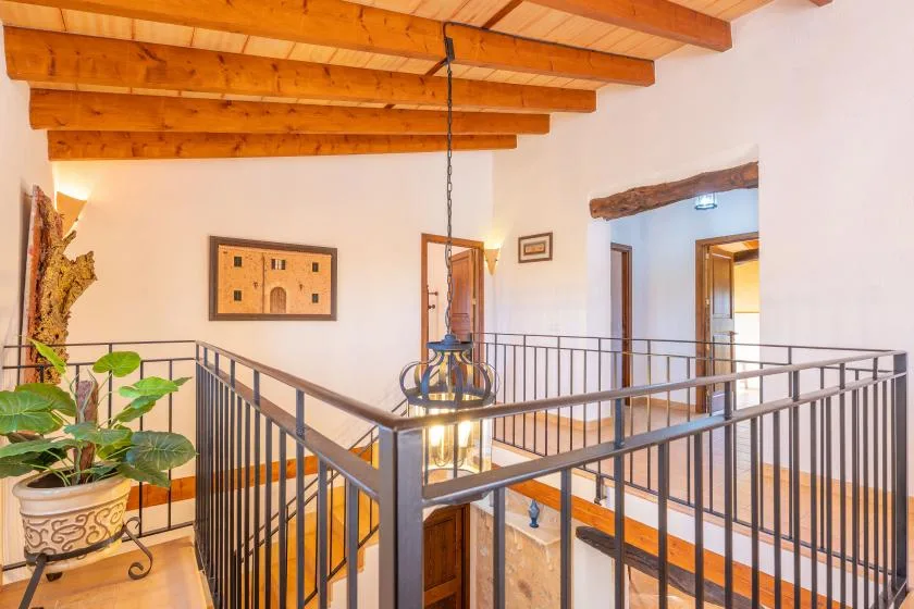 Un descansillo interior con barandillas metálicas bajo vigas de madera a la vista.
