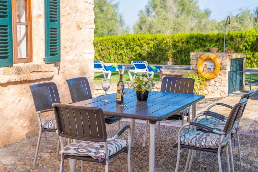 Una zona de comedor al aire libre con mesa y asientos junto a un edificio de piedra.