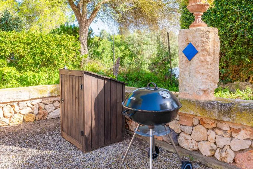 Una zona de barbacoa al aire libre con una parrilla redonda junto a un armario de madera.