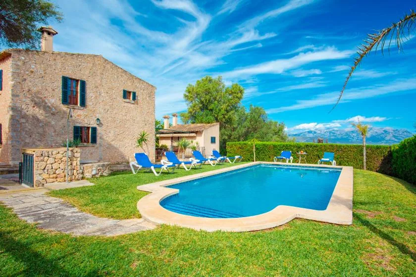 Una piscina está junto a un edificio de piedra y un césped.
