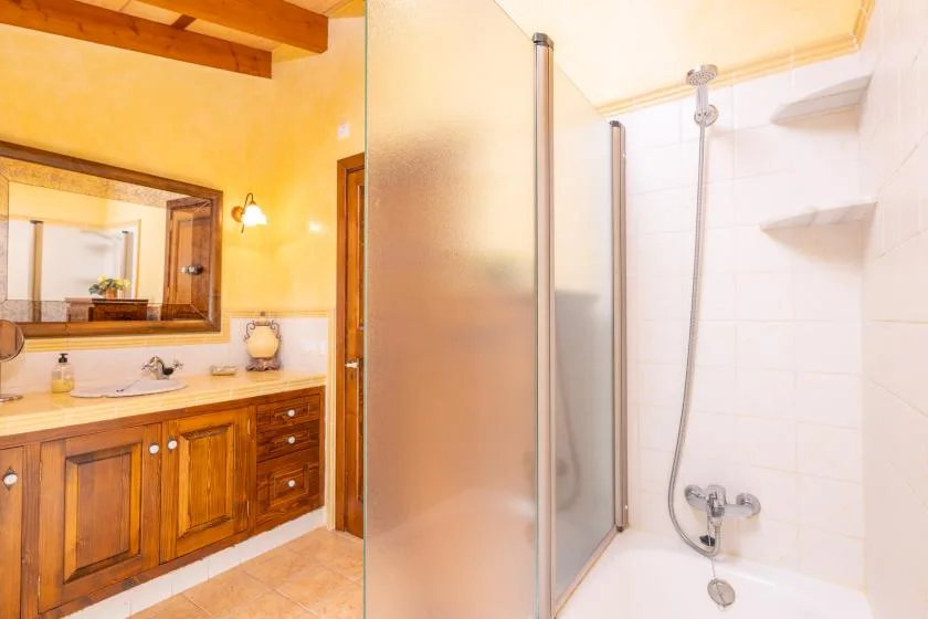 Un baño con un mueble de madera y una ducha de vidrio.