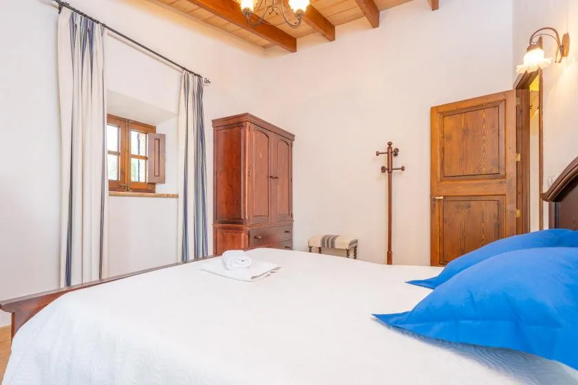Un dormitorio con una cama blanca, almohadas azules y muebles de madera.
