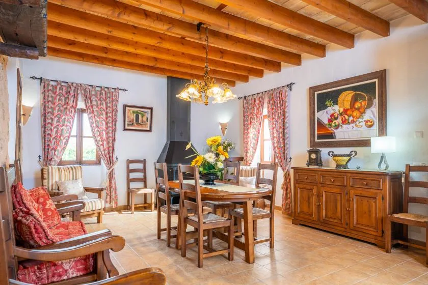 Un comedor con una mesa y sillas de madera bajo vigas de techo a la vista.