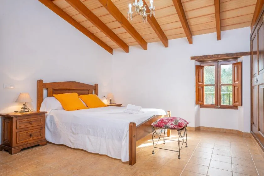 Un dormitorio con una cama de madera, mesitas de noche y una ventana.