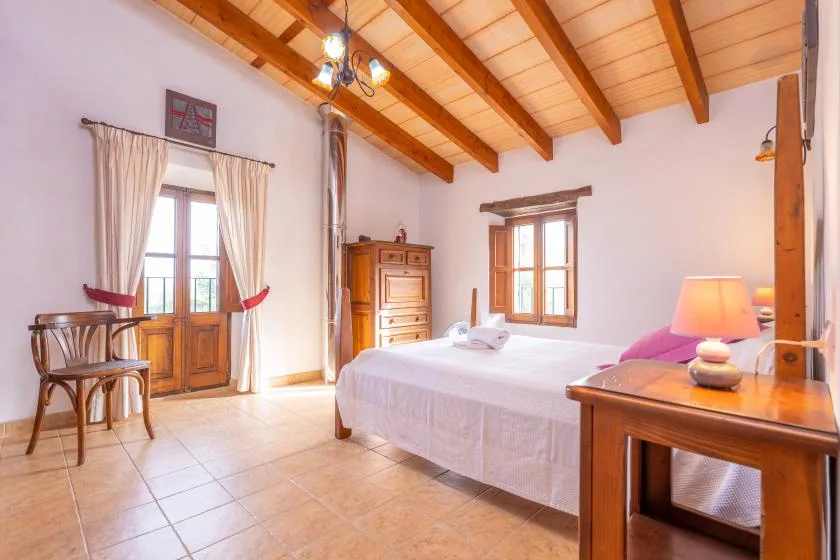 Un dormitorio con una cama, vigas de madera en el techo y una ventana.