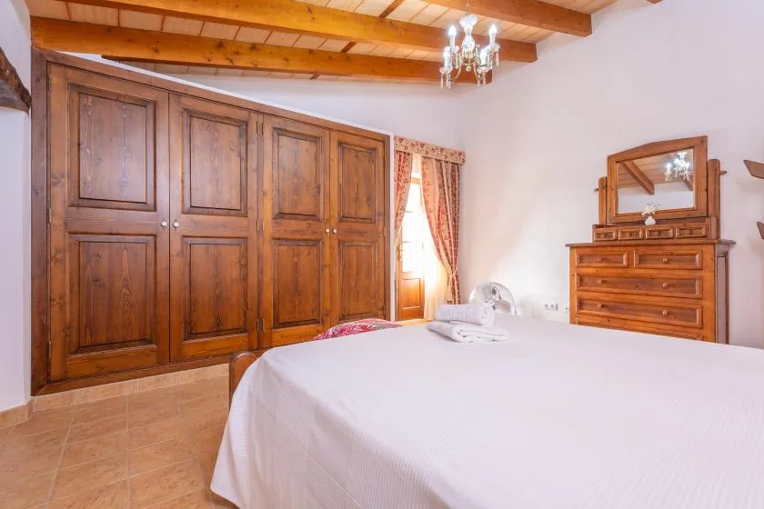Un dormitorio con una cama, armarios de madera y una cómoda.