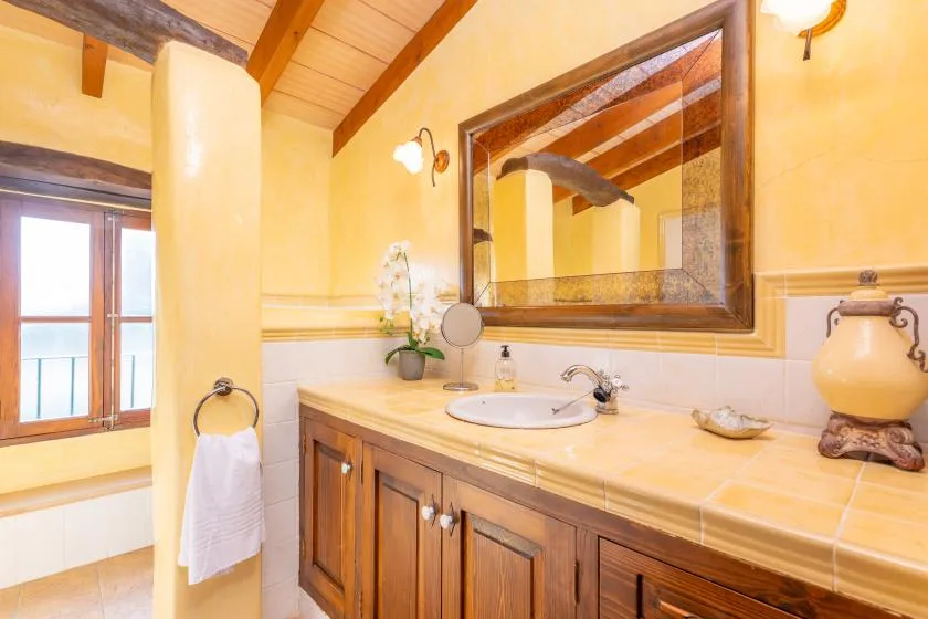 Un tocador de baño con un espejo amplio y una ventana al lado.