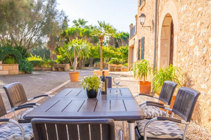 Una zona de comedor al aire libre con mesa y sillas junto a un edificio de piedra.