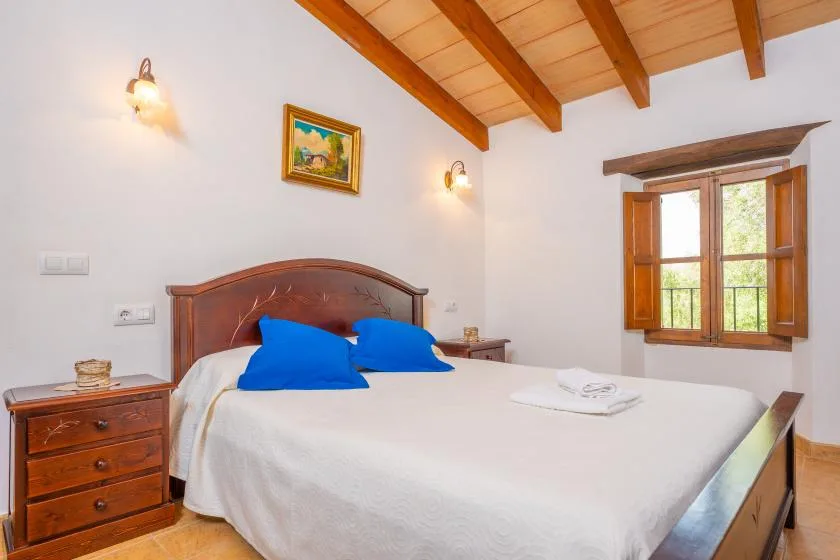 Un dormitorio con una cama doble, almohadas azules y techo de madera.