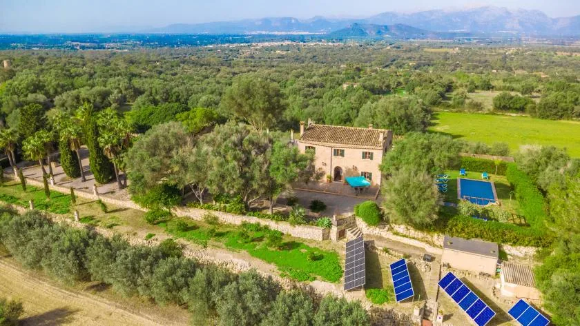 Una propiedad rural está rodeada de árboles y campos, con paneles solares cerca.