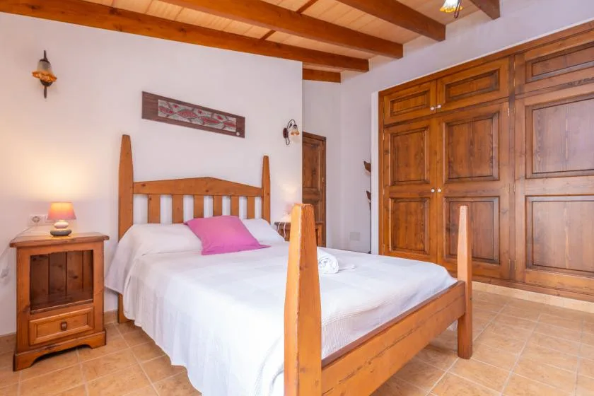 Un dormitorio con una cama de madera, ropa de cama blanca y armarios empotrados de madera.