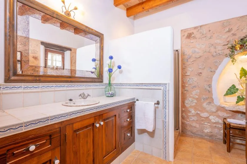 Un tocador de baño con una encimera larga con lavabo y un espejo grande enmarcado.