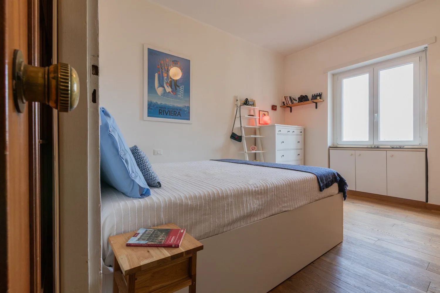 Un dormitorio con una cama, una cómoda y una ventana grande.