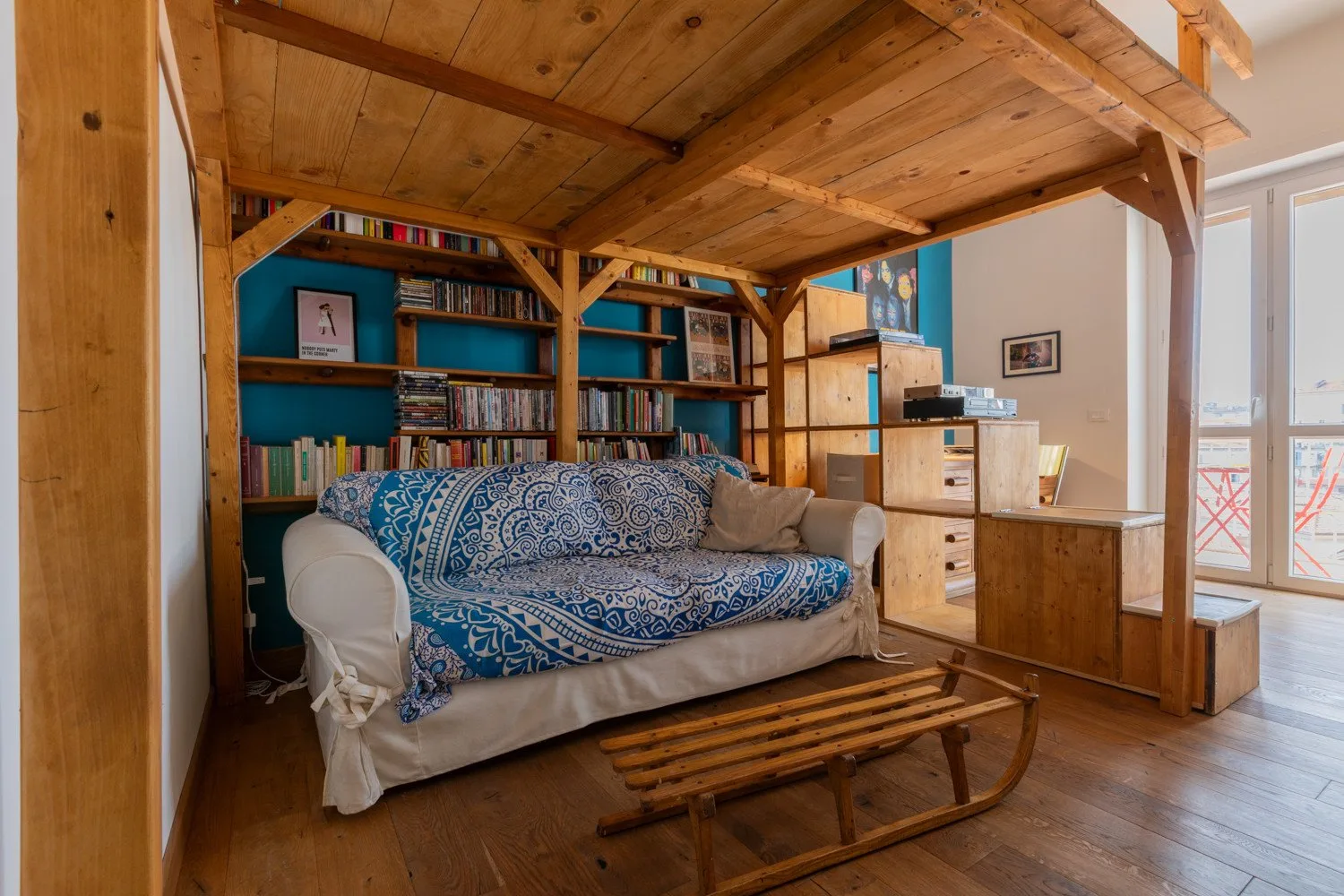 Una sala de estar con un sofá estampado azul bajo una estructura de madera elevada.