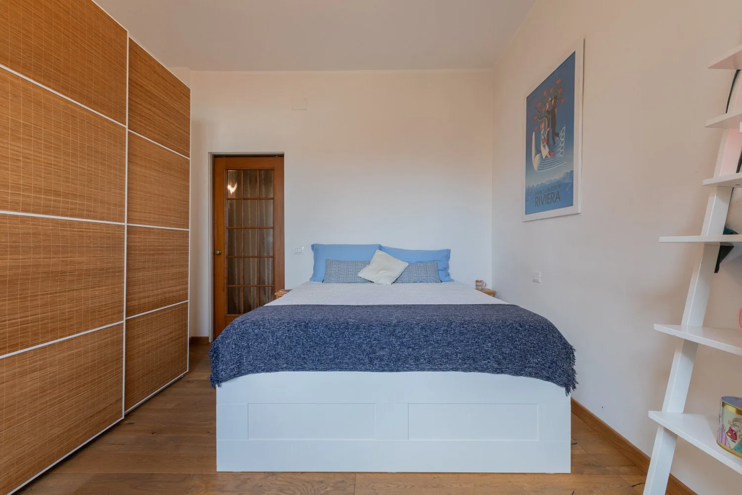 Un dormitorio con una cama cubierta por una manta azul y un armario.