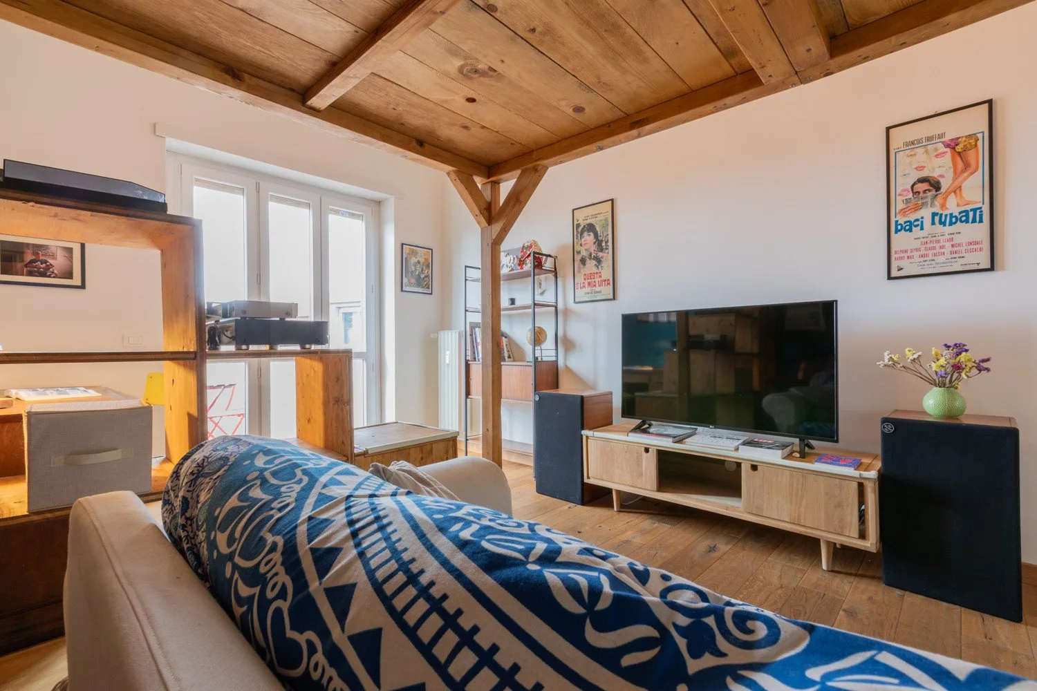 Una sala de estar con televisor, asientos y techo revestido de madera.