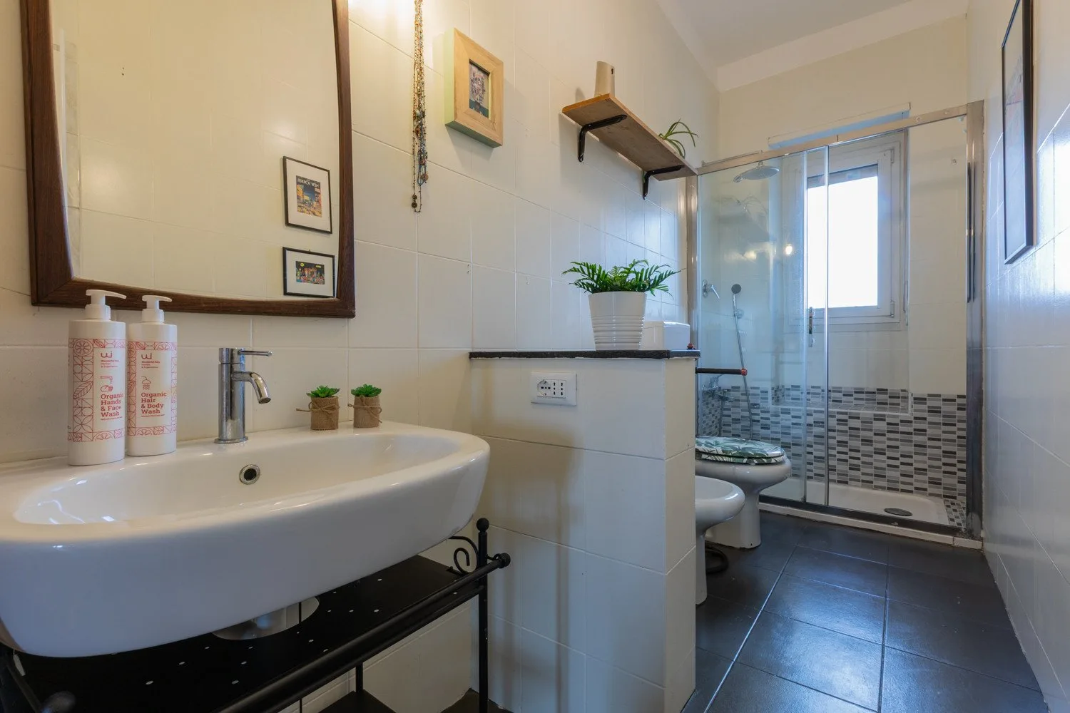 Un baño alicatado con lavabo, inodoro y ducha de mampara de vidrio.