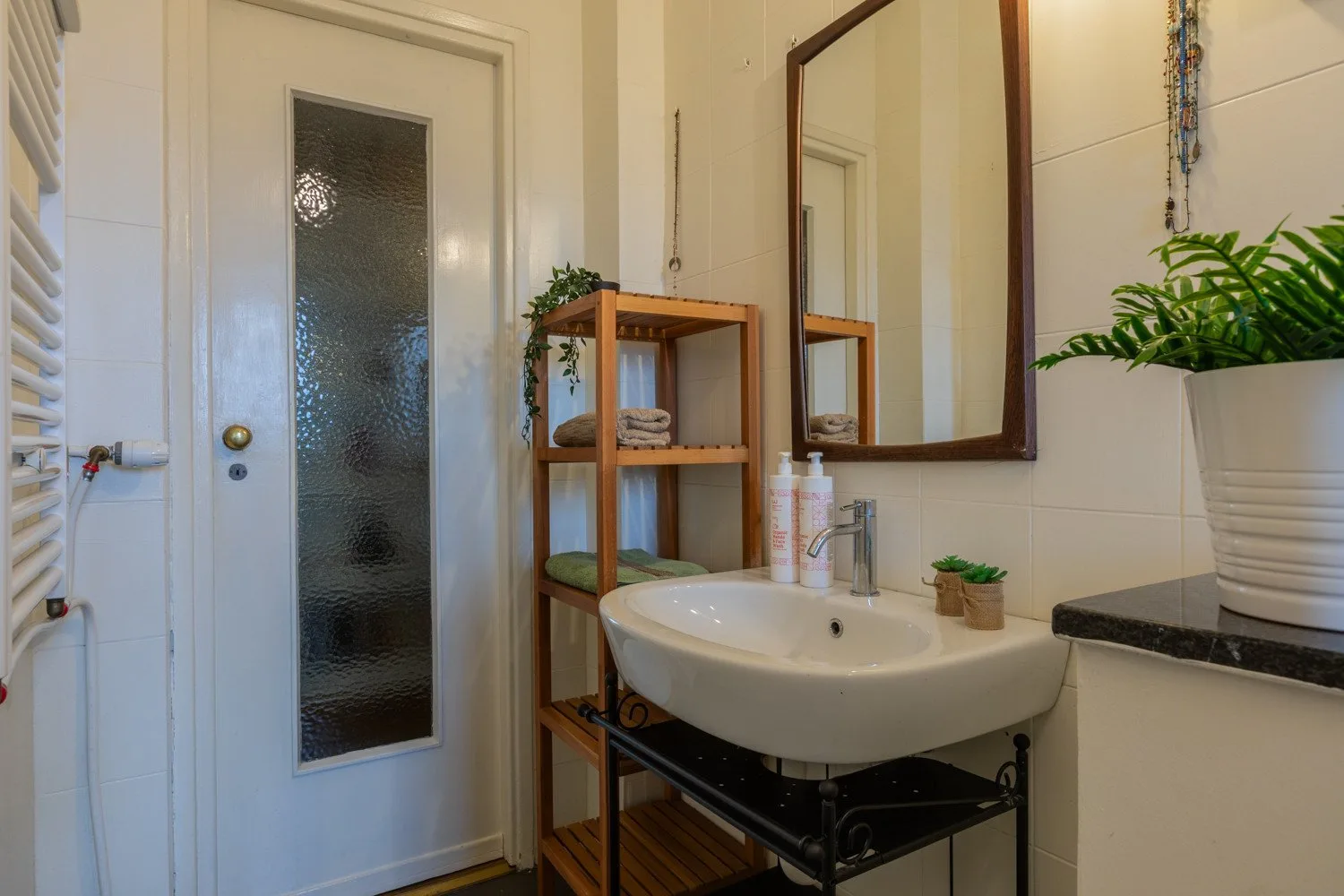Baño luminoso con lavabo, espejo y puerta de vidrio esmerilado.
