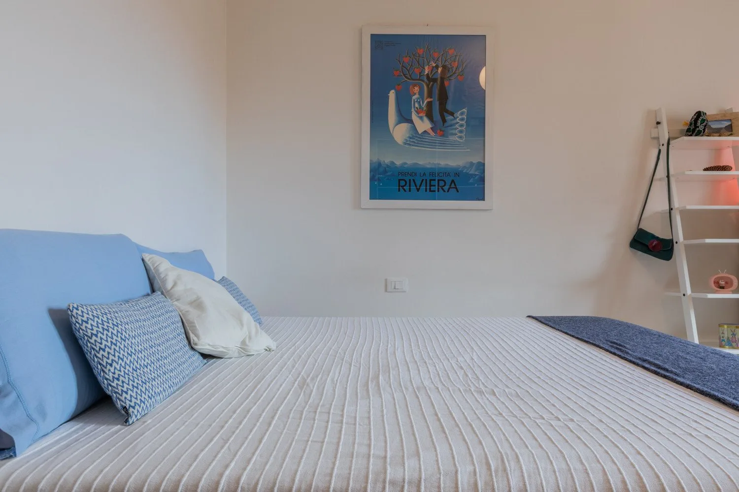 Un dormitorio con una cama bien tendida y un póster enmarcado en la pared.