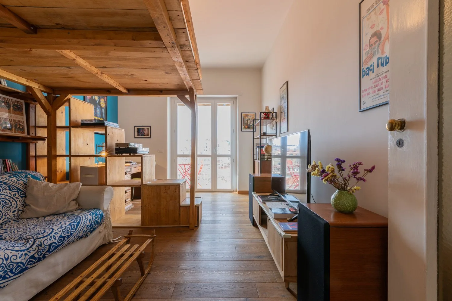 Una sala de estar con un sofá estampado, estanterías de madera y un televisor.