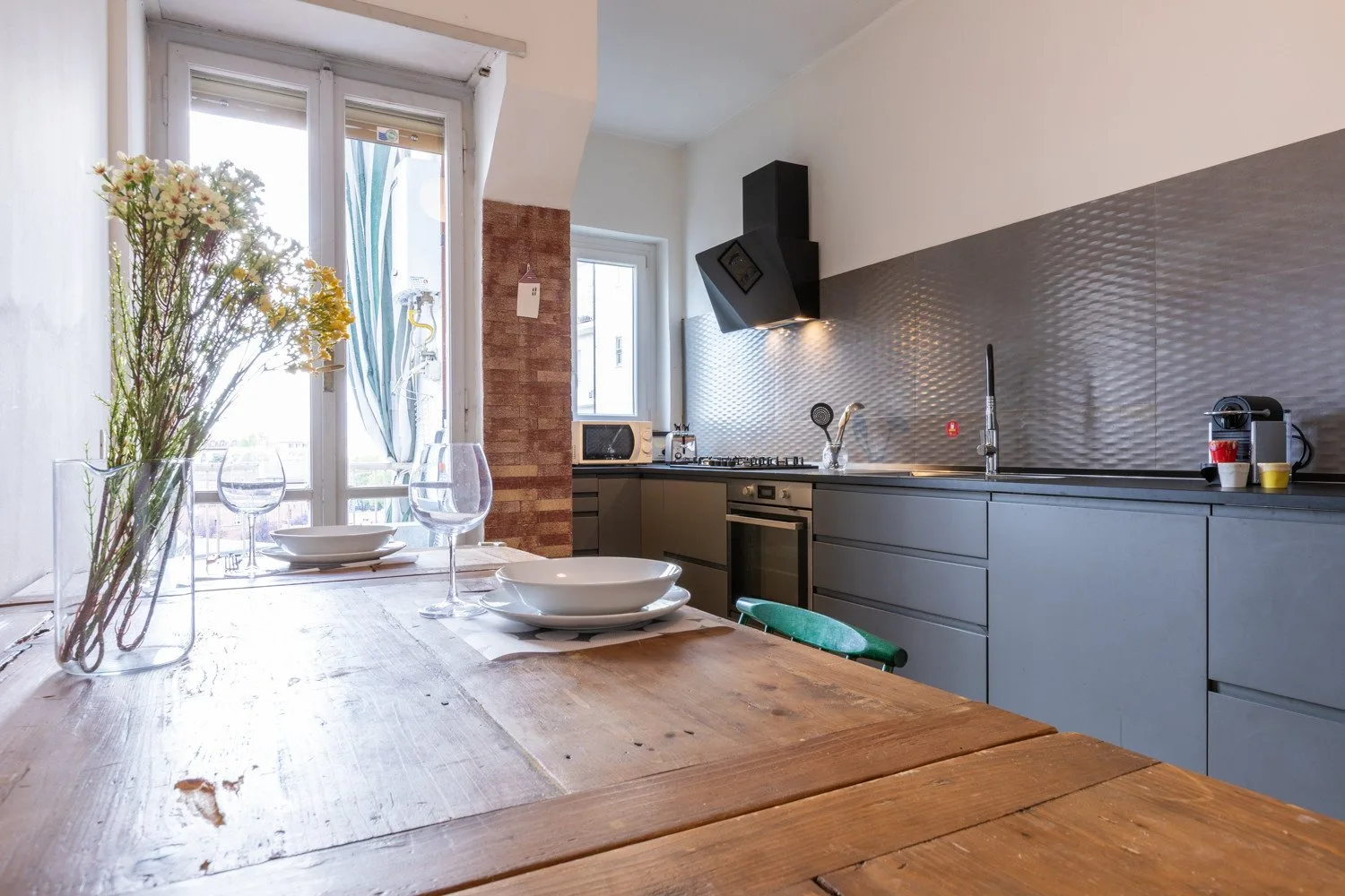 Una cocina luminosa con una mesa de comedor de madera y gabinetes grises.