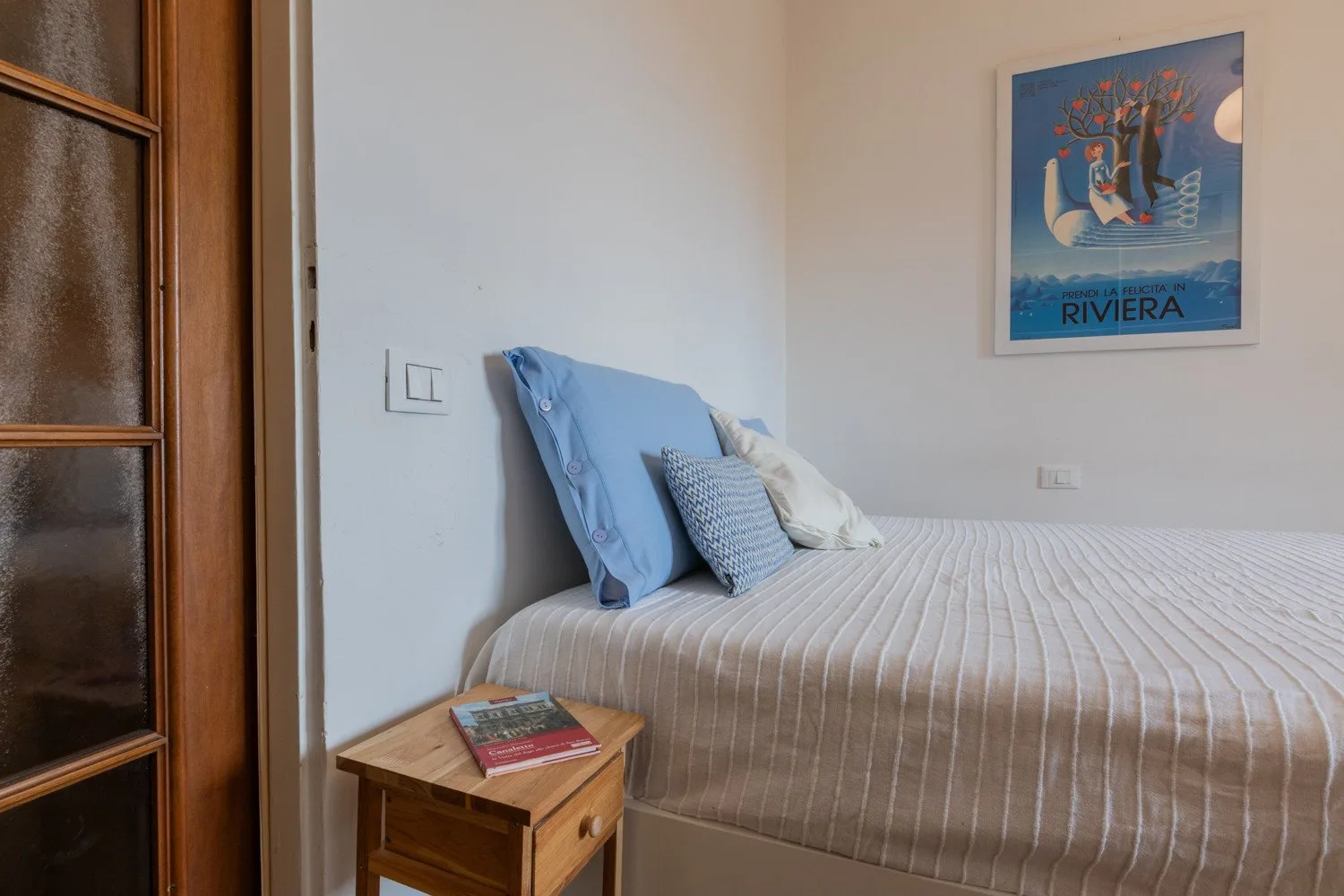 Un dormitorio con una cama bien tendida y un póster enmarcado en la pared.