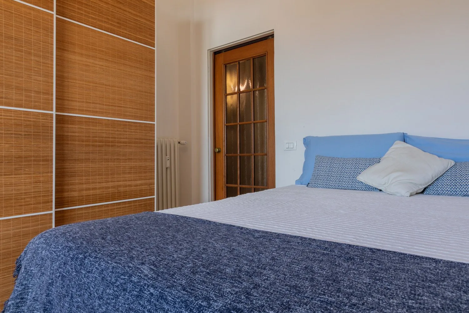 Un dormitorio con una cama bien hecha y una puerta de madera.