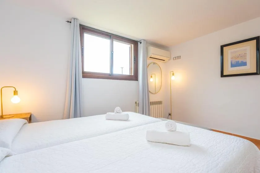 Un dormitorio con camas blancas, una ventana y luces de pared.