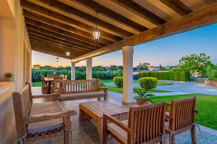 Un patio cubierto con asientos de madera da a un jardín ajardinado.