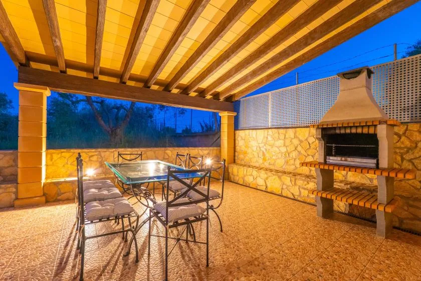 Una zona exterior cubierta con mesa, asientos y una barbacoa de piedra.