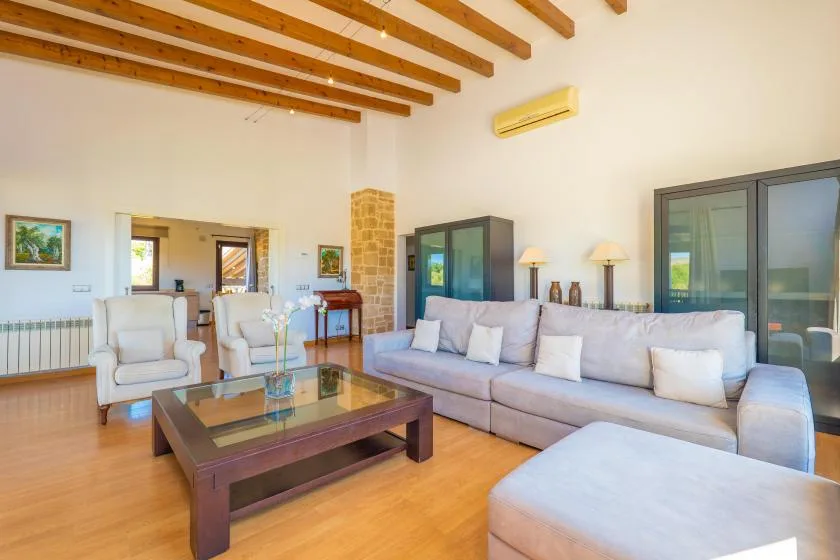 Una sala luminosa con sofá seccional, sillones y una mesa de centro con tapa de vidrio.