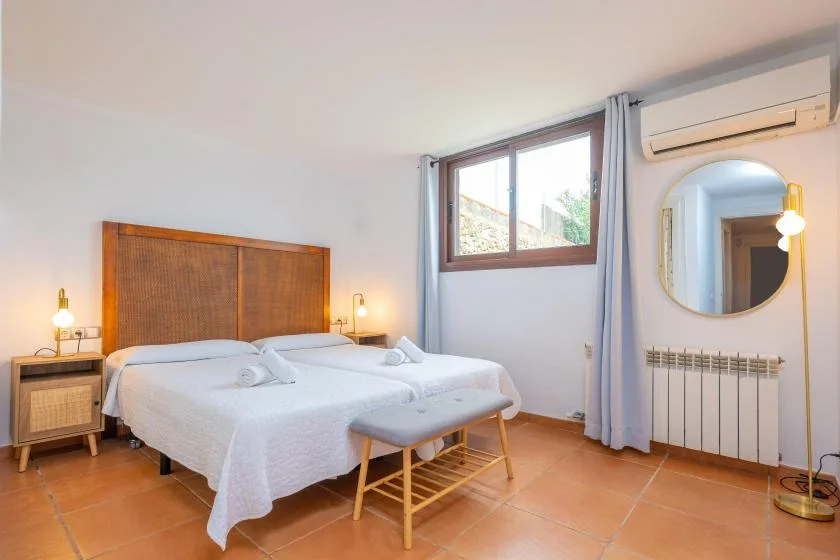 Un dormitorio con dos camas, una ventana y un espejo redondo en la pared.