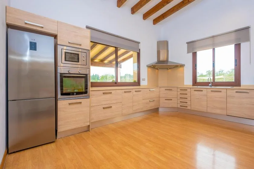 Una cocina luminosa con gabinetes de madera, electrodomésticos de acero inoxidable y ventanas.