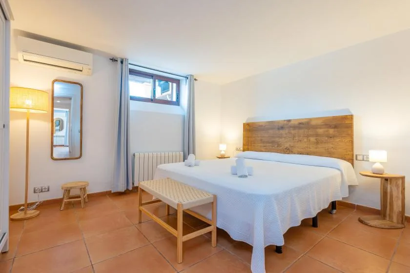 Un dormitorio con cama doble, cabecero de madera y lámparas de noche.