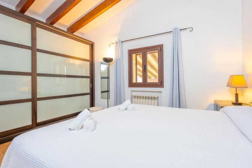 Un dormitorio luminoso con una cama grande y una ventana con marco de madera.