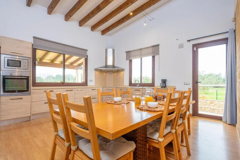 Un comedor con una mesa de madera y sillas junto a una cocina.