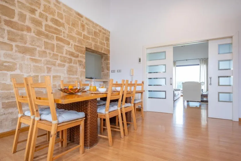 Un comedor con una mesa de madera y sillas junto a una pared de piedra.