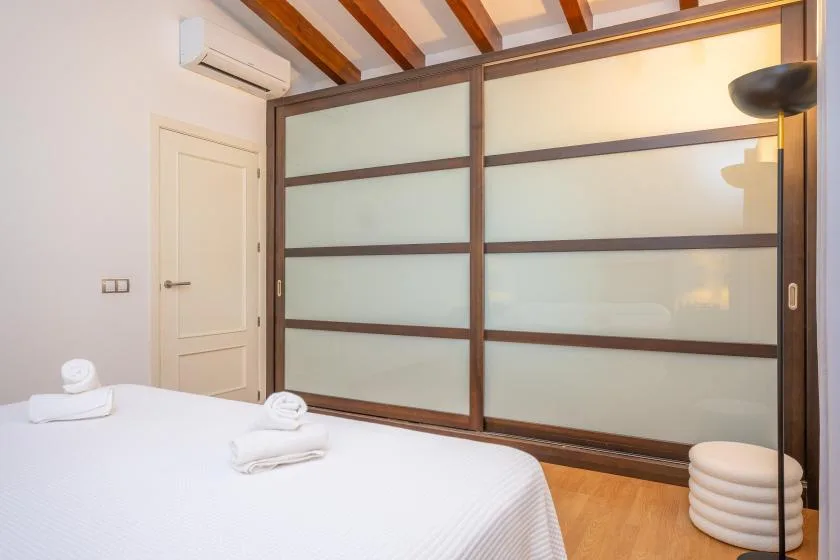 Un dormitorio con una cama blanca junto a un gran panel de vidrio esmerilado.