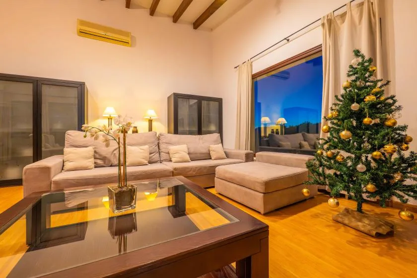 Una sala de estar con asientos, una mesa de centro de vidrio y un árbol de Navidad decorado.