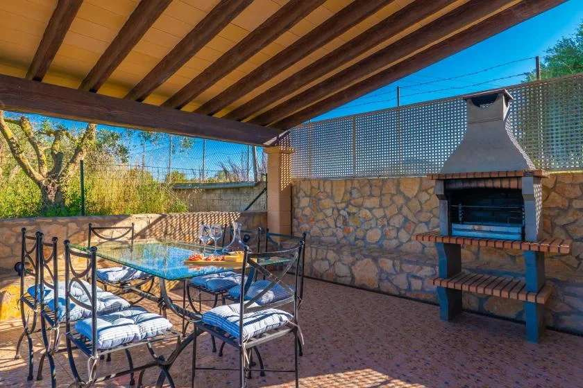 Un comedor exterior cubierto con mesa, asientos y una barbacoa de piedra.