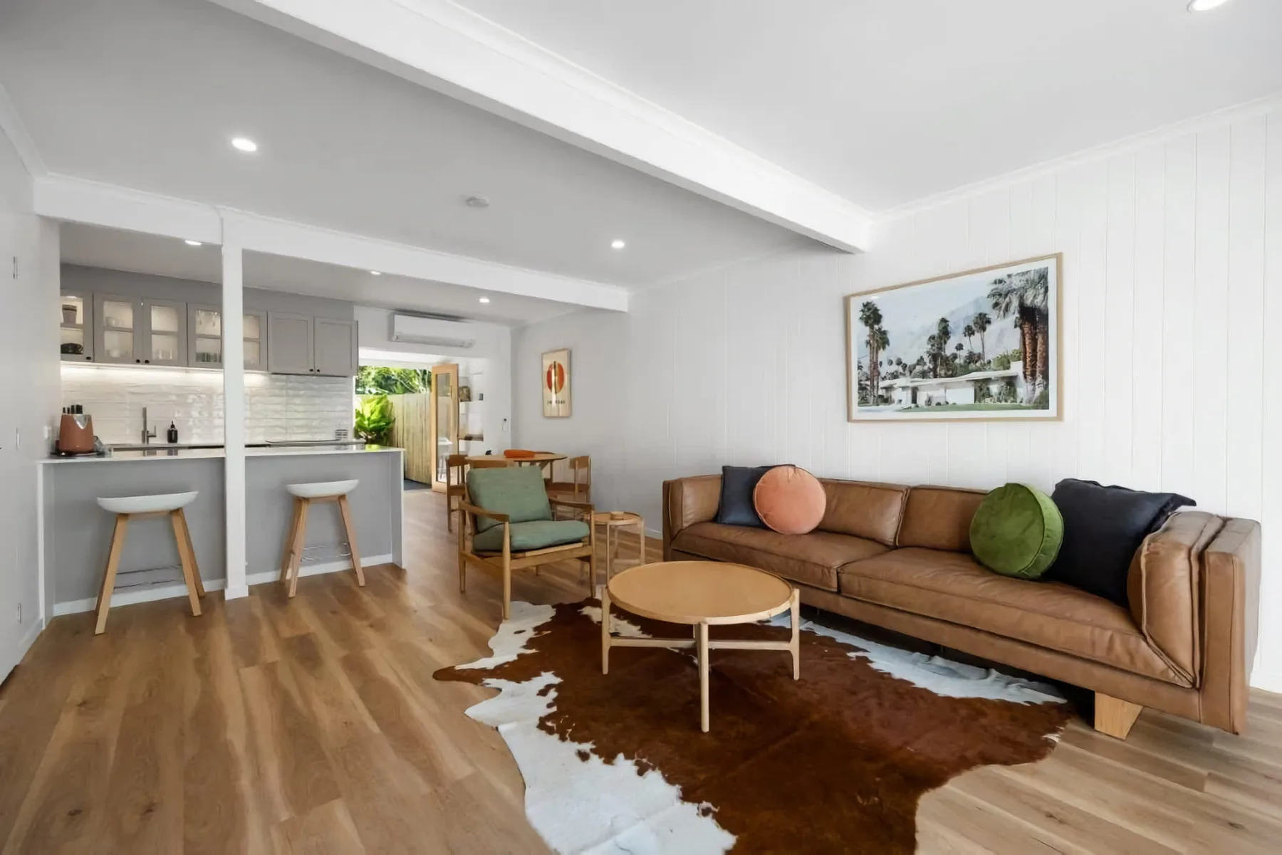 An open-plan living room with a brown sofa and a kitchen counter.