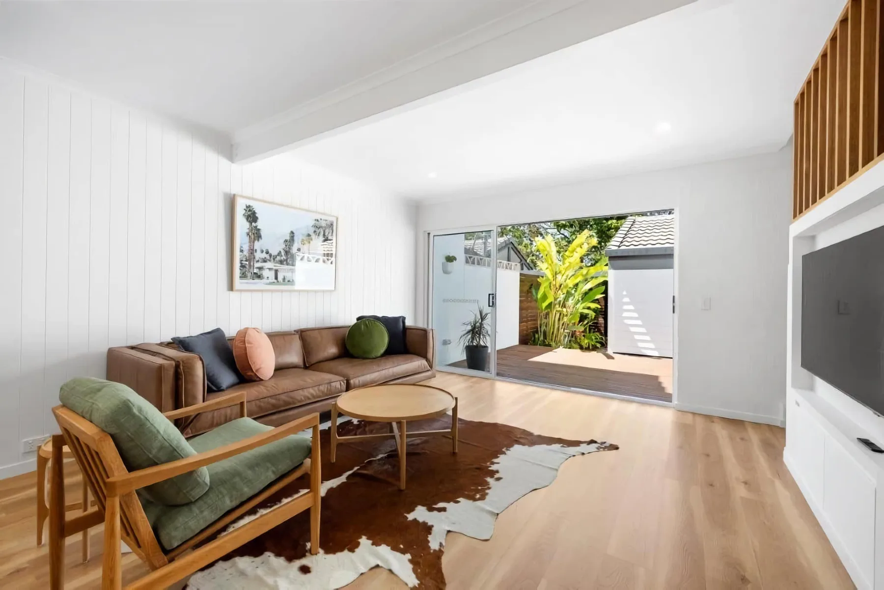 A bright living room with seating around a low table and a sliding glass door.