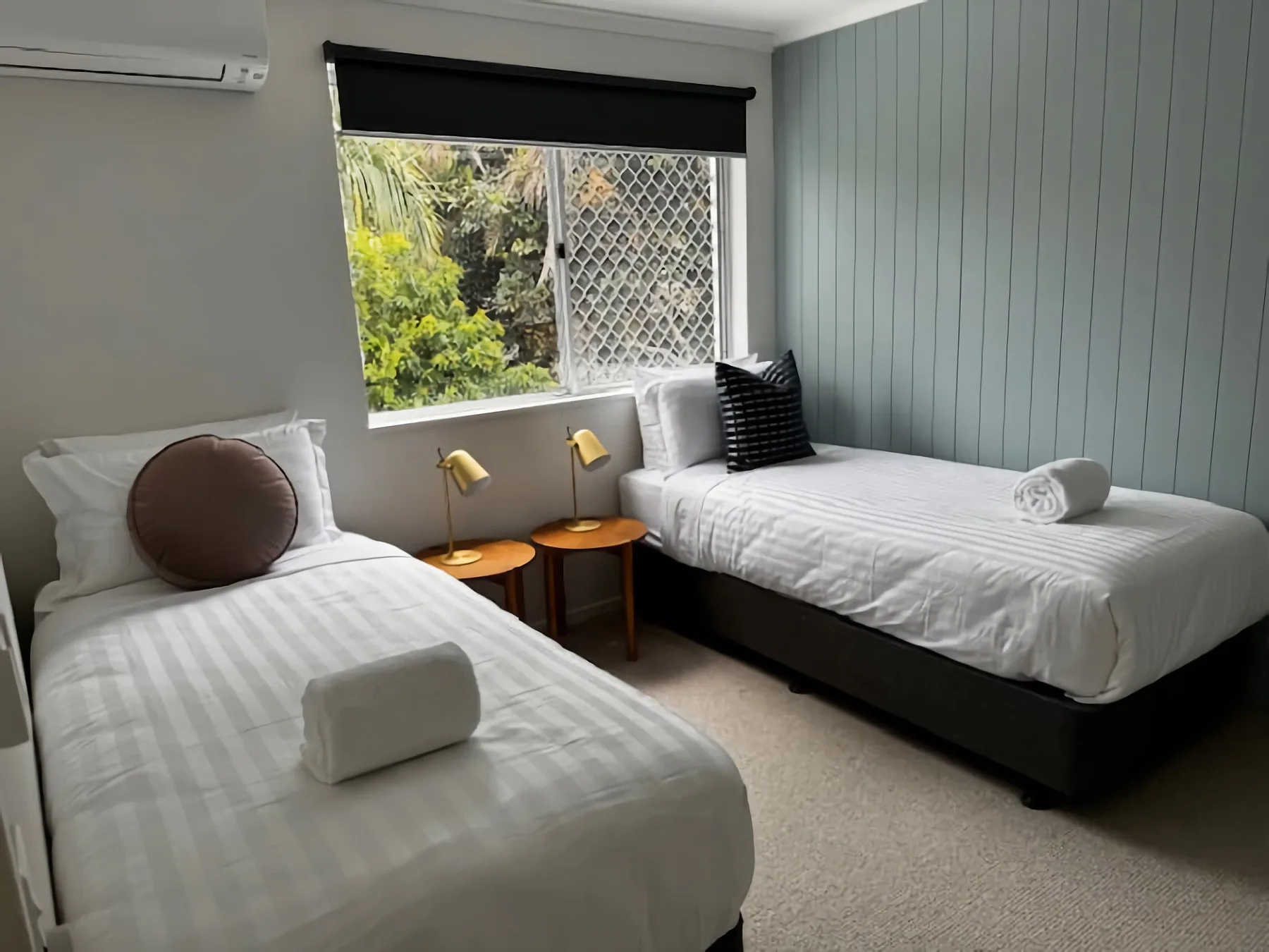 A twin bedroom with white bedding and a window overlooking greenery.