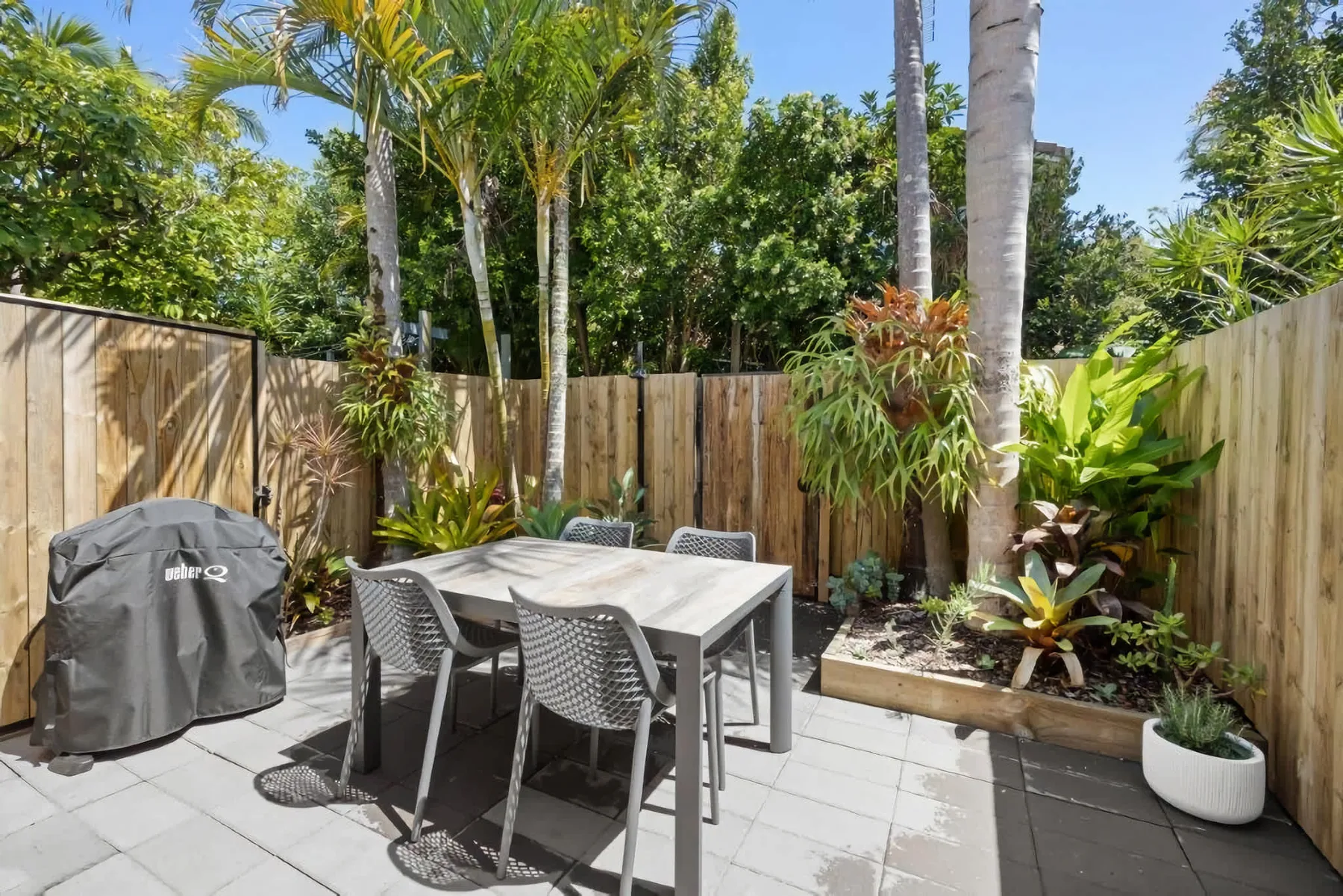 An outdoor dining area with a table and chairs on a tiled patio.
