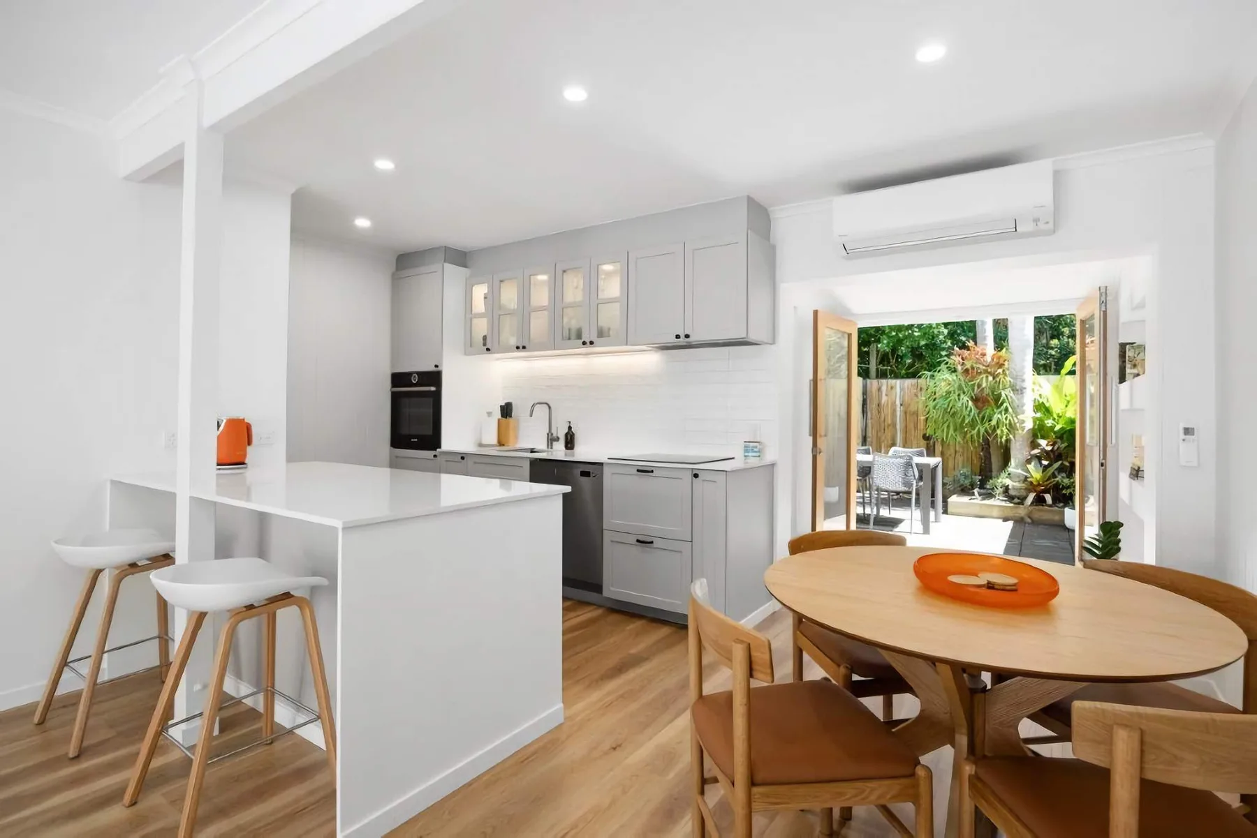 An open kitchen and dining area with a wooden table and stools.