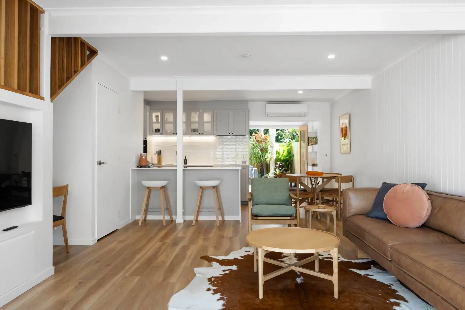 A bright living room with seating, a coffee table, and an open kitchen.