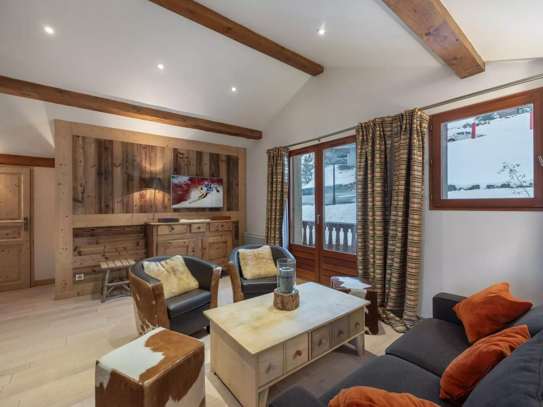 A living room with seating, a wooden coffee table, and windows overlooking a snowy landscape.