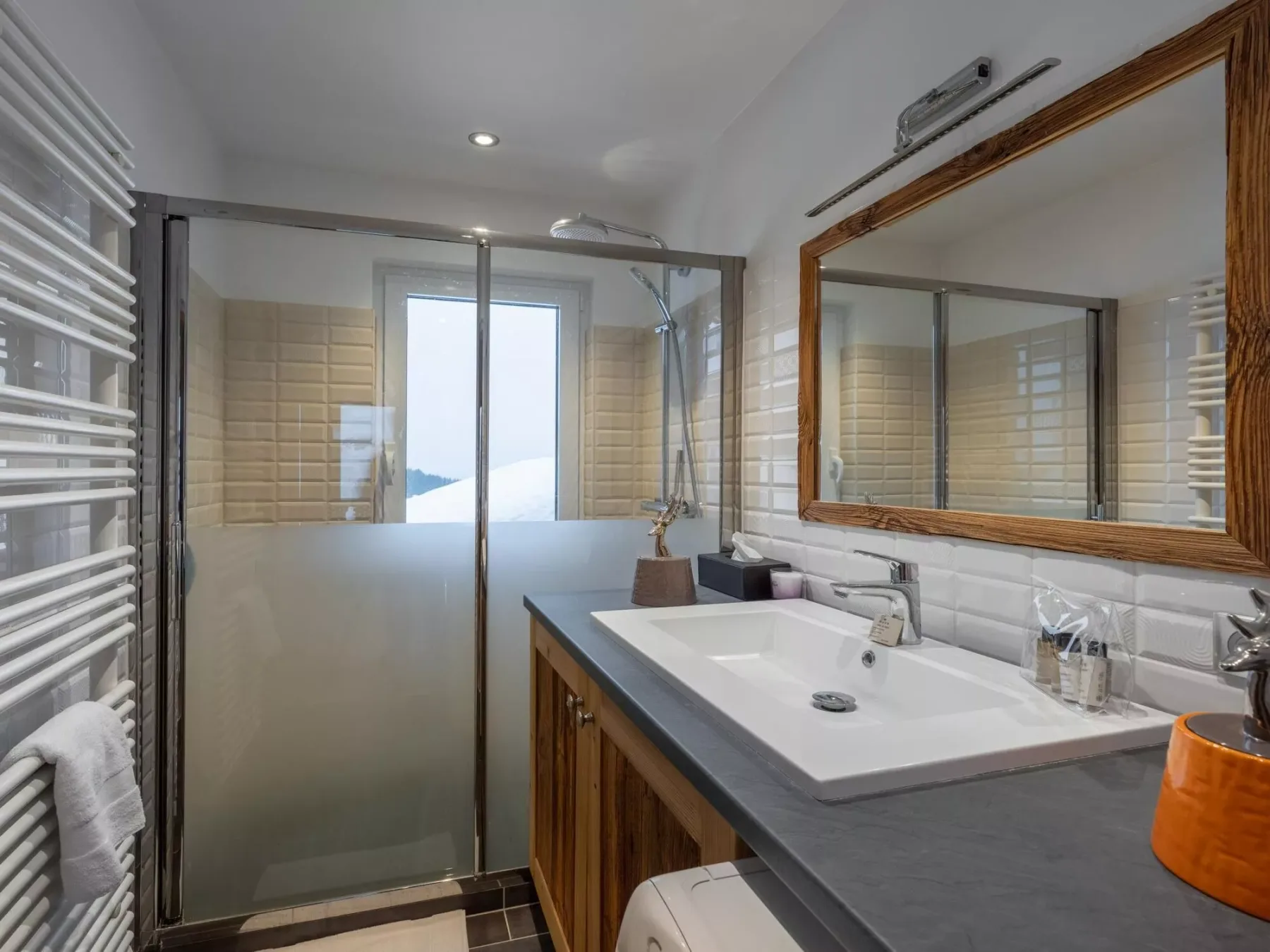 Un baño con una ducha de vidrio y una encimera larga con lavabo.