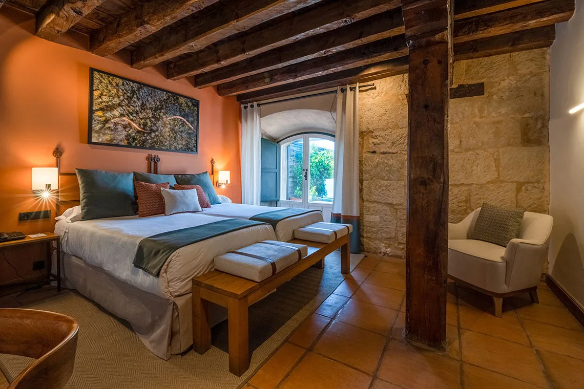 Habitación del hotel con cama, escritorio y balcón.