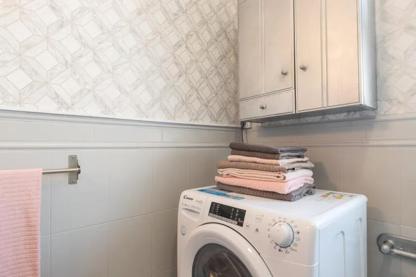 A laundry area with a washing machine beneath a wall cabinet.